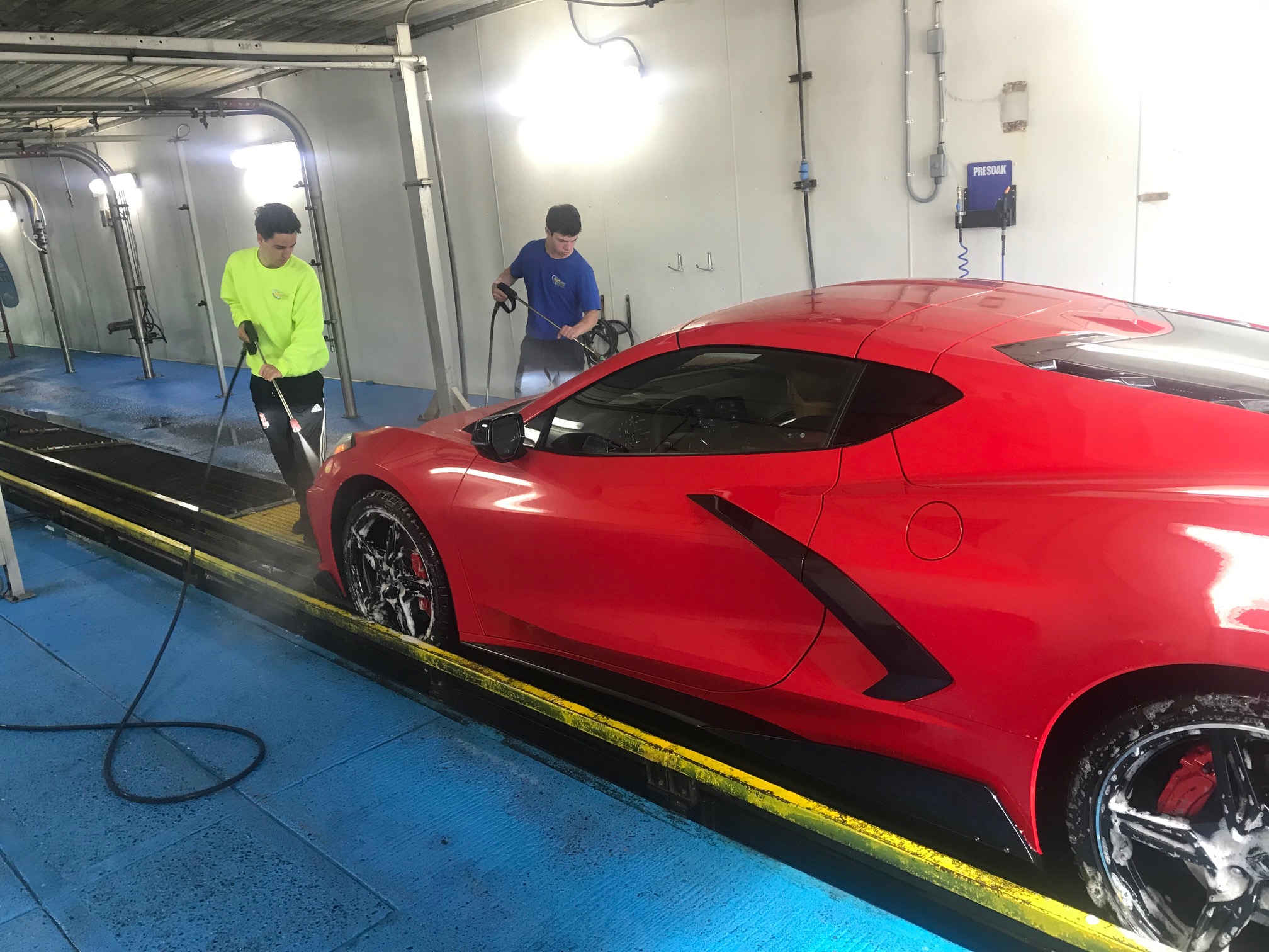 CDA Car Wash detail team hand-washing a red Corvette